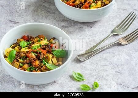 Linsen- und Auberginenragu mit Tagliatelle-Pasta und frischem Basilikum - gesundes vegetarisches Essen Stockfoto