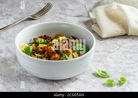 Linsen- und Auberginenragu mit Tagliatelle-Pasta und frischem Basilikum - gesundes vegetarisches Essen Stockfoto