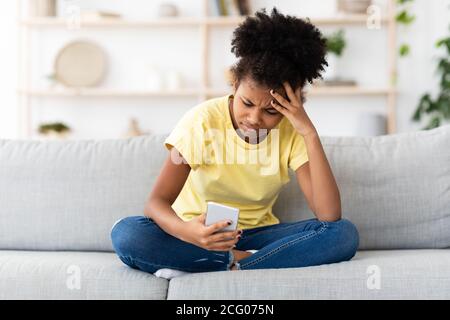 Unglücklich Kind Mädchen Halten Handy Nachrichten Zu Hause Lesen Stockfoto