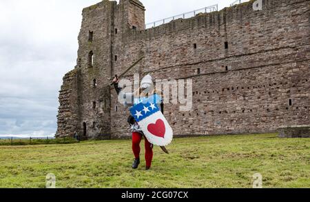 Mann gekleidet als mittelalterlicher Ritter mit Schwert, Hemet & Schild mit Gesichtsmaske bei der Wiedereröffnung nach dem Lockdown, Tantallon Castle, East Lothian, Schottland, Großbritannien Stockfoto