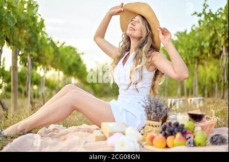 Glückliche Frau mit einem Picknick im Weingarten. Großer Hut smilling und verträumten Look Stockfoto