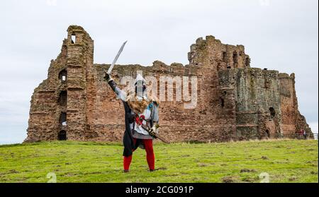 Mann gekleidet als mittelalterlicher Ritter mit Schwert & Helm mit Gesichtsmaske bei der Wiedereröffnung nach dem Lockdown, Tantallon Castle, East Lothian, Schottland, Großbritannien Stockfoto