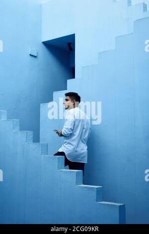 Der junge latein hält sein Handy blau Gebäude Stockfoto