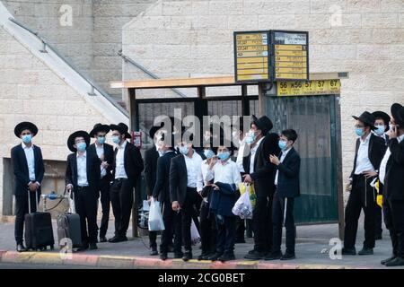 Jerusalem, Israel. September 2020. Ultraorthodoxe jüdische Männer warten an einer Bushaltestelle, um aus Jerusalems Stadtteil Ramat Shlomo zu fliehen, Minuten bevor eine von der Regierung verhängte Nachtflucht in 8 Jerusalemer Stadtteilen und 40 ‘red' Städten landesweit in Kraft tritt, die als COVID-19 Hotspots gelten. Fast eine halbe Million Menschen werden von dieser Ausgangssperre jede Nacht von 19:00 bis 05:00 Uhr am nächsten Tag eingeschränkt werden, verboten von Versammlungen von über 10 Personen in geschlossenen Räumen und 20 in offenen Bereichen, Schließung des Bildungssystems und Unternehmen ab 19:00 Uhr. Israel führt die Welt in der neuen täglichen Infektionsrate Stockfoto