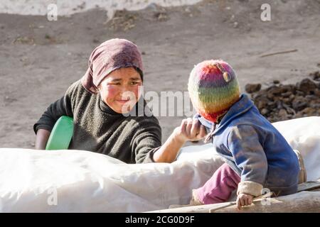 Jhong, Nepal - 17. November 2015: Mutter ruft das kleine nepalesische Kind an, das in der Nähe des Hauses spielt. Stockfoto