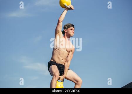 Low-Abschnitt Porträt von unkenntlich Mann Heben zwei schwere Kettlebells Mit kräftiger Anstrengung während des Trainings im Fitnessstudio Stockfoto