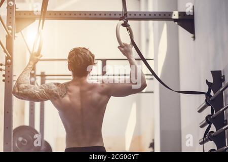 Kräftig tätowiert in weiß unbeschriftete Tank T-Shirt männlichen Athleten zeigt Calisthenic Moves close up Pullup Hold bei Medium Move On Zugstange Stockfoto