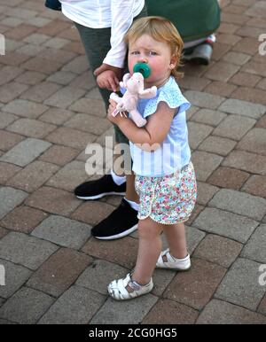 Ein junges Mädchen hält die Hand ihrer Mutter und klammert sich an ein Spielzeug, während die Familie Santa Fe, New Mexico, besucht. Stockfoto