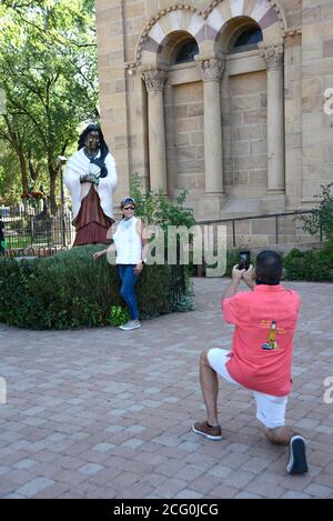 Touristen fotografieren vor einer Statue von Kateri Tekakwitha, der ersten Indianerin, die von der katholischen Kirche heilig gesprochen wurde, in Santa Fe, NM. Stockfoto