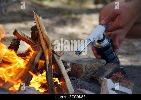 Hand hält manul Gasbrenner in der Nähe von Brennholz Stockfoto