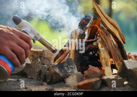 Hand hält manul Gasbrenner in der Nähe von Brennholz Stockfoto