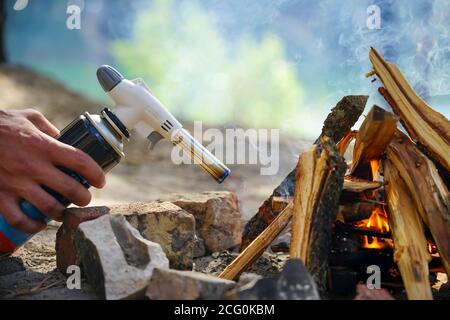 Hand hält manul Gasbrenner in der Nähe von Brennholz Stockfoto