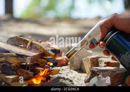 Hand hält manul Gasbrenner in der Nähe von Brennholz Stockfoto