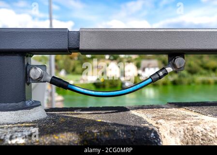 Ein Erdungskabel, das die Metallgeländer an der Eisenbahnbrücke verbindet. Stockfoto