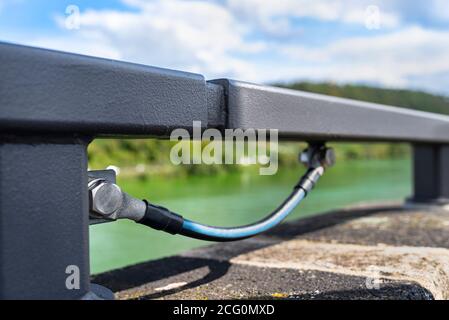 Ein Erdungskabel, das die Metallgeländer an der Eisenbahnbrücke verbindet. Stockfoto