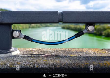 Ein Erdungskabel, das die Metallgeländer an der Eisenbahnbrücke verbindet. Stockfoto