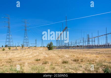 Blick auf Hochspannungs-Kraftwerk und Hochspannungs-Kabel Kreuzung Türme in grünen Rasen... Stockfoto