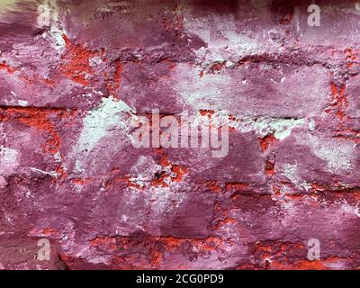 Blick auf isolierte raue Ziegelwand in weiß, rosa, lila und weiß lackiert Stockfoto