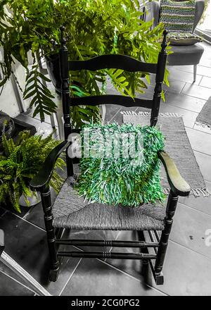 Blick auf leeren alten Holzschaukelstuhl mit grünem Kissen, Pflanzen im deutschen Wohnzimmer Stockfoto
