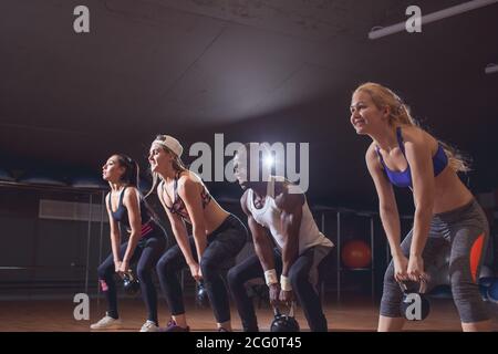 Männer und Frauen mit Trainer am kettlebell Functional Training im Fitness Center Stockfoto