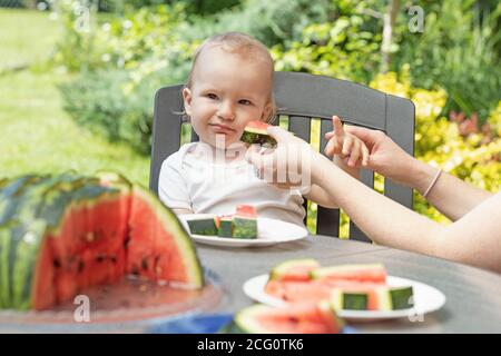 Cute Baby junge isst Wassermelone an einem Tisch im Freien sitzen. Stockfoto