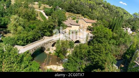 Panoramablick auf ein kleines Dorf im Südosten Frankreichs. An einem sonnigen Tag fließt ein Fluss unter einer alten Steinbrücke Stockfoto