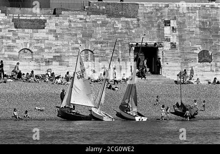 AJAXNETPHOTO. 1974. OLD PORTSMOUTH, GROSSBRITANNIEN. - HEISSE MAUERN - DIE MENSCHEN ENTSPANNEN SICH AM STEINIGEN STRAND UNTER DEN HEISSEN MAUERN DES ALTEN PORTSMOUTH, TEIL DER BEFESTIGUNGSANLAGEN HENRY VIII GEBAUT, UM DIE STADT IM 16. JAHRHUNDERT DEFND. ES WAR DURCH DAS LOCH (RECHTS IN DER MITTE) GENANNT SALLY PORT, VICE ADMIRAL HORATIO NELSON ZULETZT FUSS AUF ENGLISCHEN BODEN VOR DEM START ZU HMS SIEG FÜR IM SEPTEMBER 1805. FOTO:JONATHAN EASTLAND/AJAX REF:741604 27 35 Stockfoto