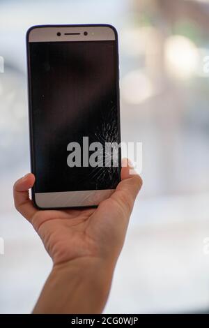 Zerbrochenes Glas Smartphone. Selektiver Fokus. Das Mädchen hält in ihrer Hand ein versehentlich gebrochenes Telefon. Risse auf dem Smartphone-Bildschirm. Stockfoto