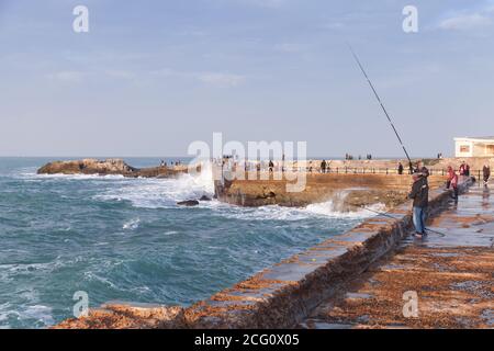 Alexandria, Ägypten - 13. Dezember 2018: Landschaft mit alten Küstensteinbefestigungen. Fischer sind auf nassen Pier Stockfoto