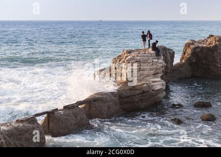 Alexandria, Ägypten - 13. Dezember 2018: Landschaft mit zerstörten Küstenbefestigungen. Jungs laufen auf Steinen in der Nähe großer plätschernden Wellen Stockfoto