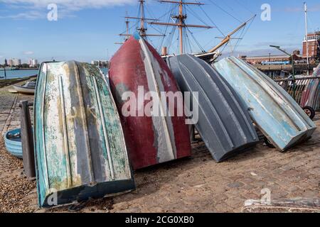 Die Rümpfe von vier alten hölzernen Ruderbooten standen auf einer Dock-Seite mit HMS Warrior angedockt in Portsmouth im Hintergrund, Portsmouth UK Stockfoto