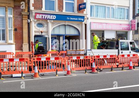 Straßendienstmitarbeiter graben eine Straße mit Verkehrsbarrieren aus Um sie herum Stockfoto