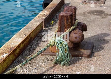 Ein Poller an einer Andockseite mit dem Seil eines Boot um es gebunden, um das Boot zu halten vertäut Der Steg Stockfoto