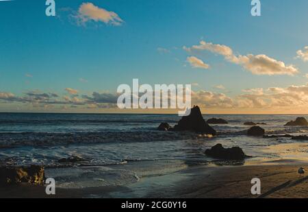 Herrlicher Malibu Sonnenuntergang im Winter LA Stil, lebendige Seestück der felsigen Küste und erhabene Wolken beleuchtet. El Matador State strandblick. . Stockfoto