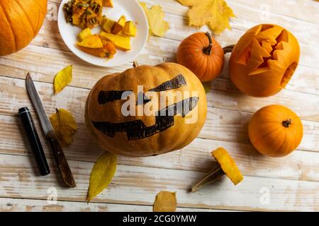 Halloween Schnitzen. Nahaufnahme von Kürbissen oder Jack-o-Laterne und Messer zu Hause. Dekoration und Urlaub Konzept Stockfoto