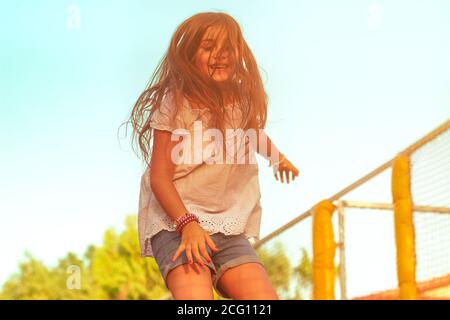 Kleines Mädchen auf Trampolin springen; positive Emotionen, glückliches Kind Stockfoto