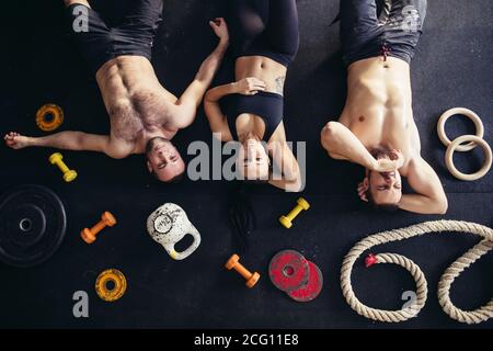 Draufsicht auf Zubehör für Fitness- und Baumsportler auf dem Boden liegend. Hanteln, Hantelscheiben, Wasserkocher, Seil, Langhanteln. Konzept für Sport oder Workout. Stockfoto