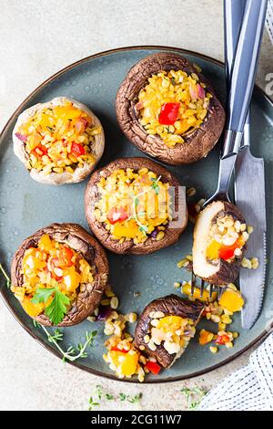 Gebackene gefüllte portobello-Pilze mit Bulgur-Pilaf und gehacktem Gemüse. Leckeres und nahrhaftes vegetarisches Gericht. Steinhintergrund, selektiver FOC Stockfoto