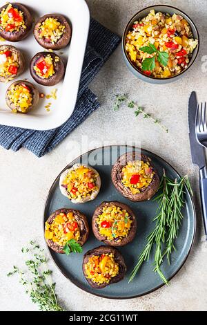 Gebackene gefüllte portobello-Pilze mit Bulgur-Pilaf und gehacktem Gemüse. Leckeres und nahrhaftes vegetarisches Gericht. Steinhintergrund, selektiver FOC Stockfoto