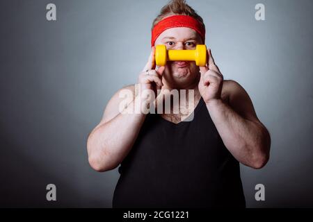 Fetter Mann mit schwarzen Shirt Training mit Hanteln und Kamera Stockfoto