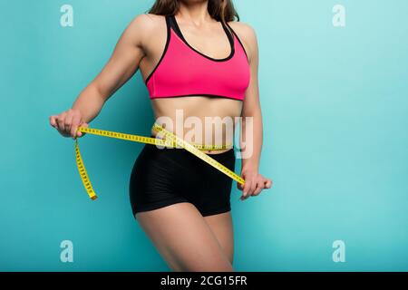 Determinated Sport Frau hat eine ausgezeichnete körperliche Form und messen mit dem Meter. Cyanfarbener Hintergrund Stockfoto