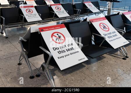 Sitzplätze blockiert mit Schildern zur Aufrechterhaltung der sozialen Distanzierung für die öffentliche Gesundheit, Terminal 3 am Flughafen Heathrow, für die Covid-19 Coronavirus-Pandemie Stockfoto