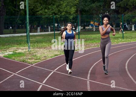 Eine schwarze und kaukasische Frauen Joggen auf der Straße in einem spezialisierten Ort. Sport - ist das Leben. Stockfoto