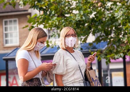 Zwei Frauen tragen passende Gesichtsmaske Abdeckung mit Mobiltelefonen Während der Pandemie von Covid 19 Stockfoto