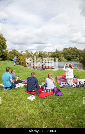 Menschen und Familien genießen Sommersonne Picknick und punting auf Die Ufer des Flusses Cam in Grantchester Meadows Cambridge Cambridgeshire