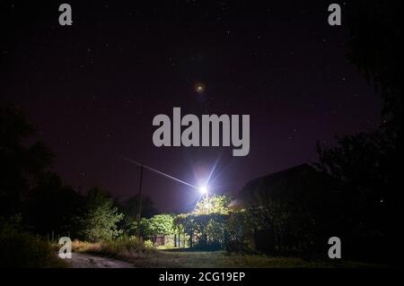 Ein Haus im Dorf unter dem Sternenhimmel von einer Laterne beleuchtet, Nacht Stockfoto