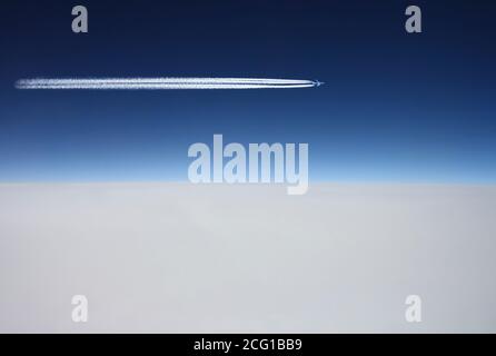 Flugzeug fliegt über weißen Wolken in einem tiefblauen Himmel Und verlassen Jet Trail Stockfoto