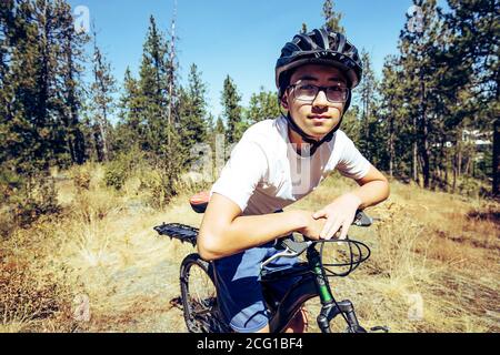 Ein Teenager-Junge macht eine Pause frm Reiten auf Trails in Nord-Idaho. Stockfoto