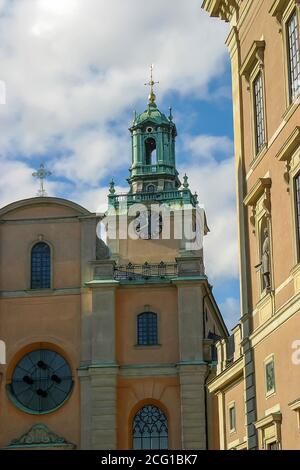 Außenansicht façade des Turms und der Wanduhr der ältesten Kirche in Stockholm in Storkyrkan, Gamla Stan. Mit blauem Himmel und weißem Wolkenhintergrund. Stockfoto