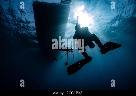 Silhouette des Tauchers unter Wasser im Ozean unter dem Boot